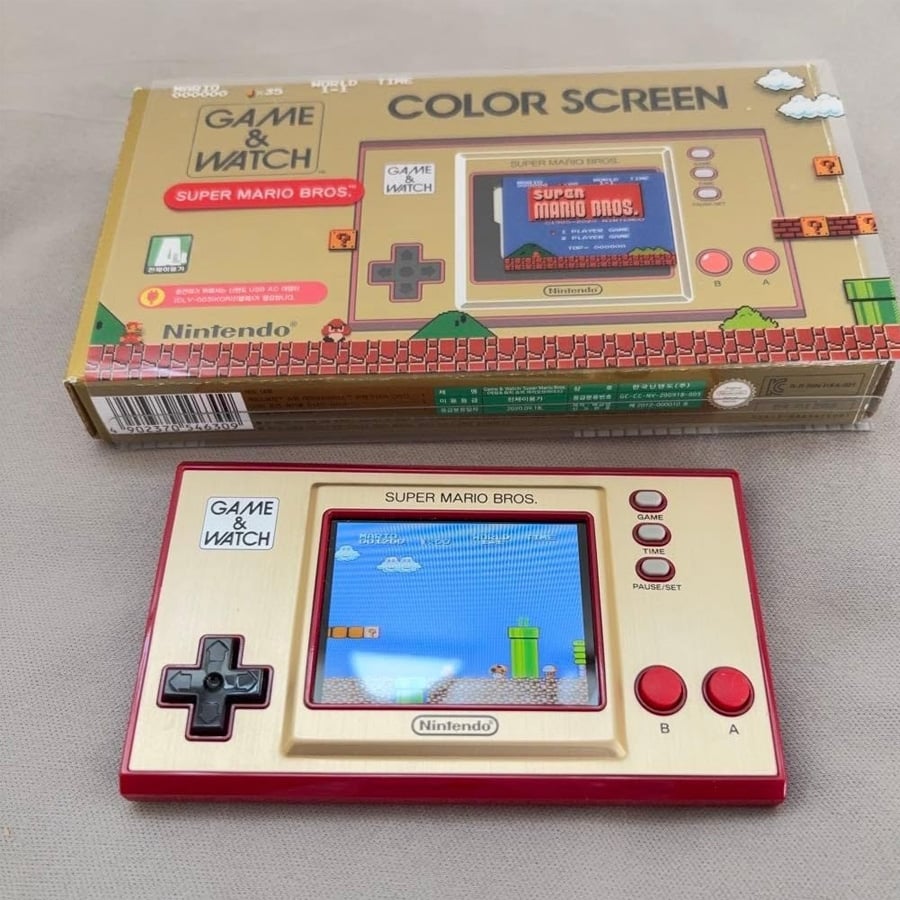 A Nintendo Game & Watch: Super Mario Bros. handheld console is shown below its matching box, with the game screen displaying a scene from Super Mario Bros.