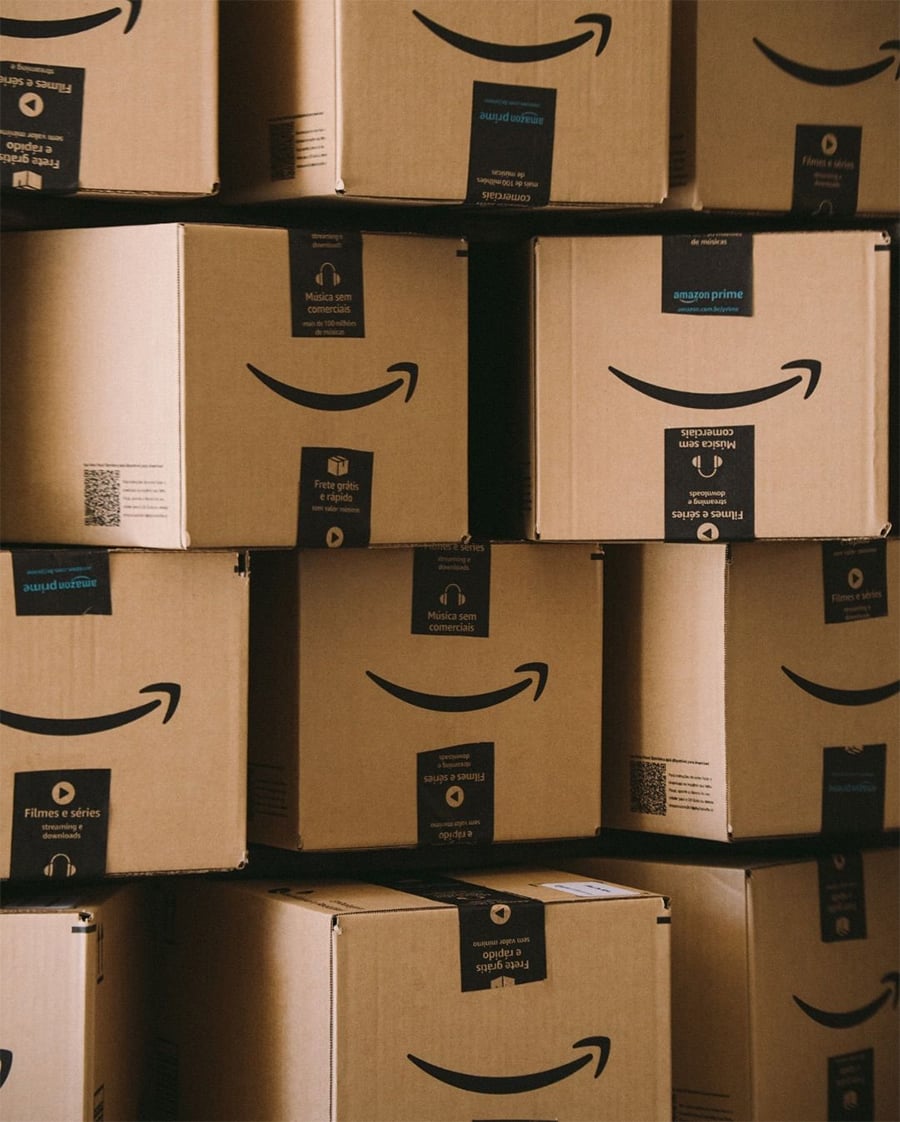 A stack of Amazon cardboard boxes with smiling logo and Amazon Prime tape, arranged in a close, tidy pattern.