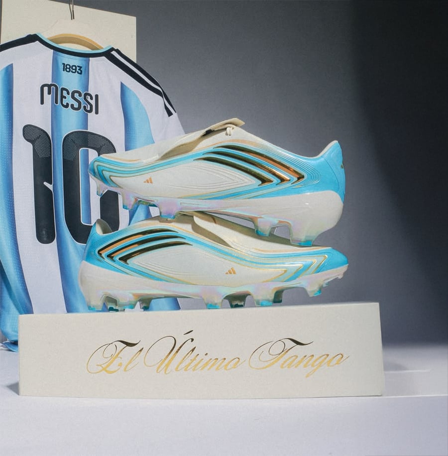A pair of blue and white soccer cleats sit on a display labeled "El Último Tango," with an Argentina jersey featuring the name "Messi" and number 10 hanging behind them.
