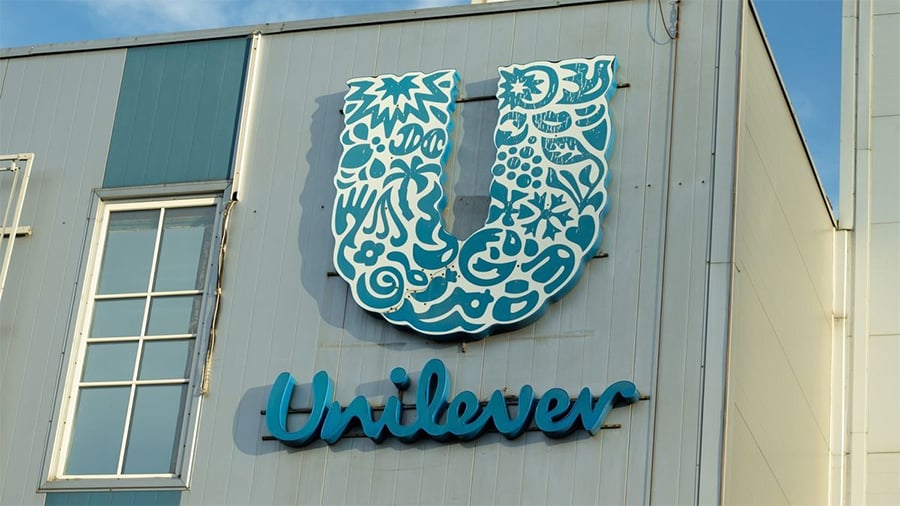The exterior of a building features a large Unilever logo with blue and white patterns above the word "Unilever" in cursive blue letters.