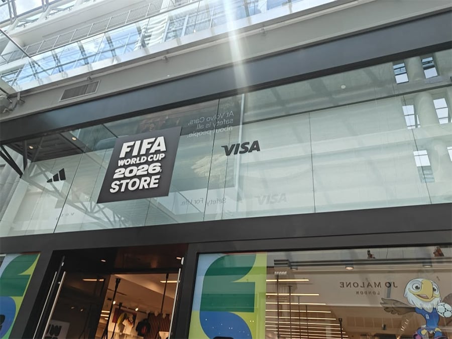 FIFA World Cup 2026 Store with a VISA logo on the glass facade, located in a modern building with sunlight streaming through the ceiling.