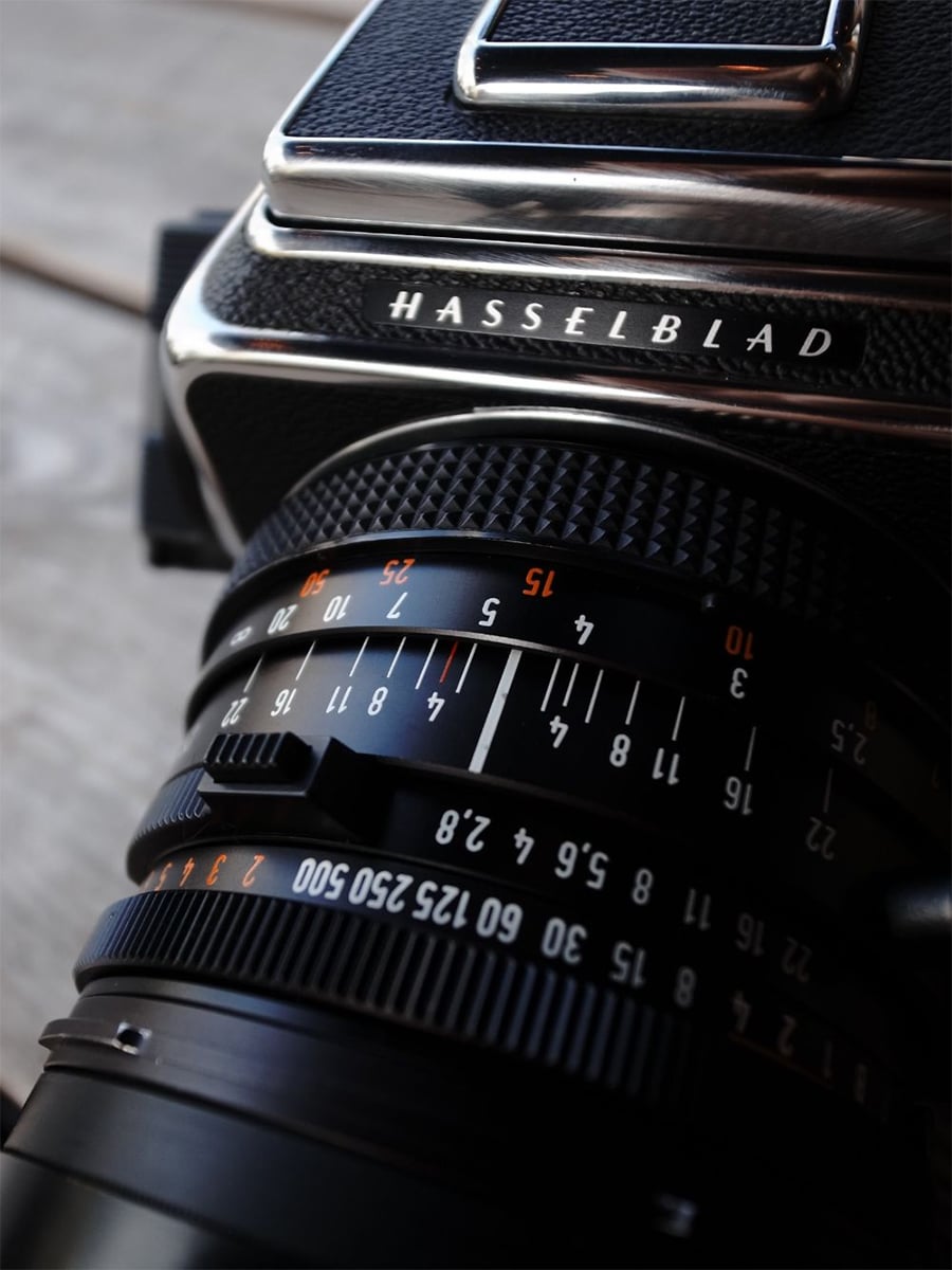 Close-up of a vintage Hasselblad camera, focusing on the lens and numbered focus and aperture rings, with the camera brand name clearly visible.