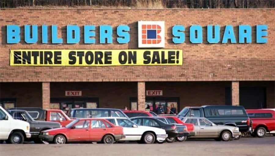 A Builders Square store with a large yellow banner reading "ENTIRE STORE ON SALE!" hangs above the entrance. Several cars are parked in front of the brick building.