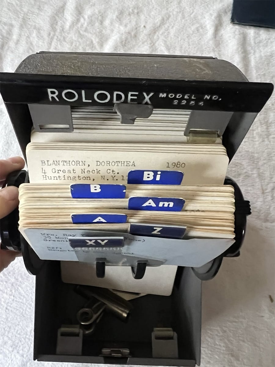 An open Rolodex showing index cards with alphabetical tabs and a card for Dorothea Blanthorn, listing an address in Huntington, NY. The Rolodex is black and sits on a white surface.