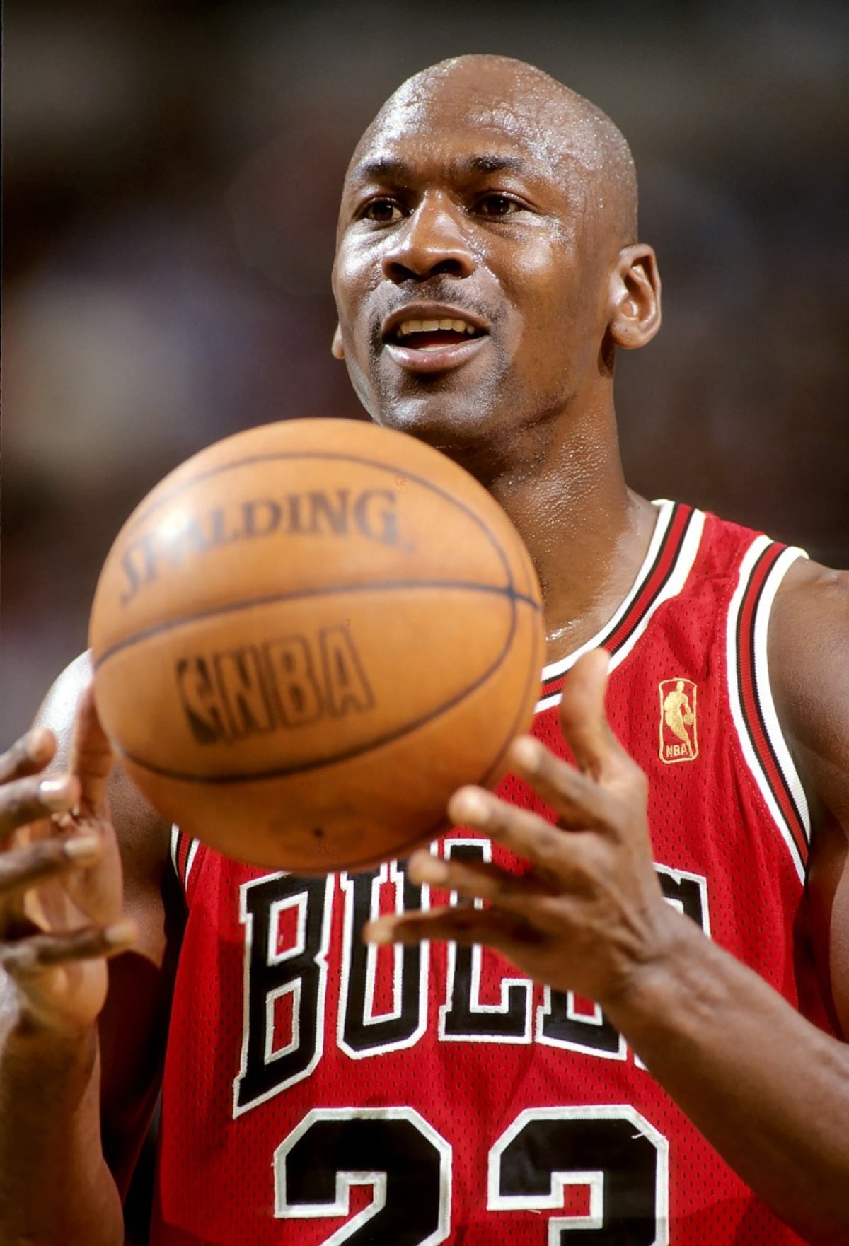 A basketball player in a red Chicago Bulls jersey, number 23, is holding a Spalding NBA basketball, appearing focused during a game.