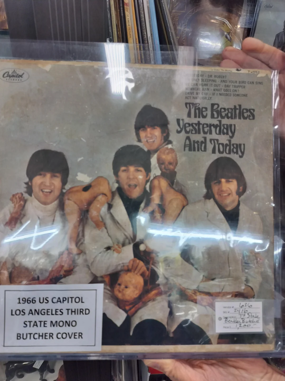 The Beatles’ “Yesterday and Today” album cover, showing the band in white coats holding doll parts and raw meat. The cover is inside protective plastic, with a label noting it’s the 1966 US “butcher cover.”