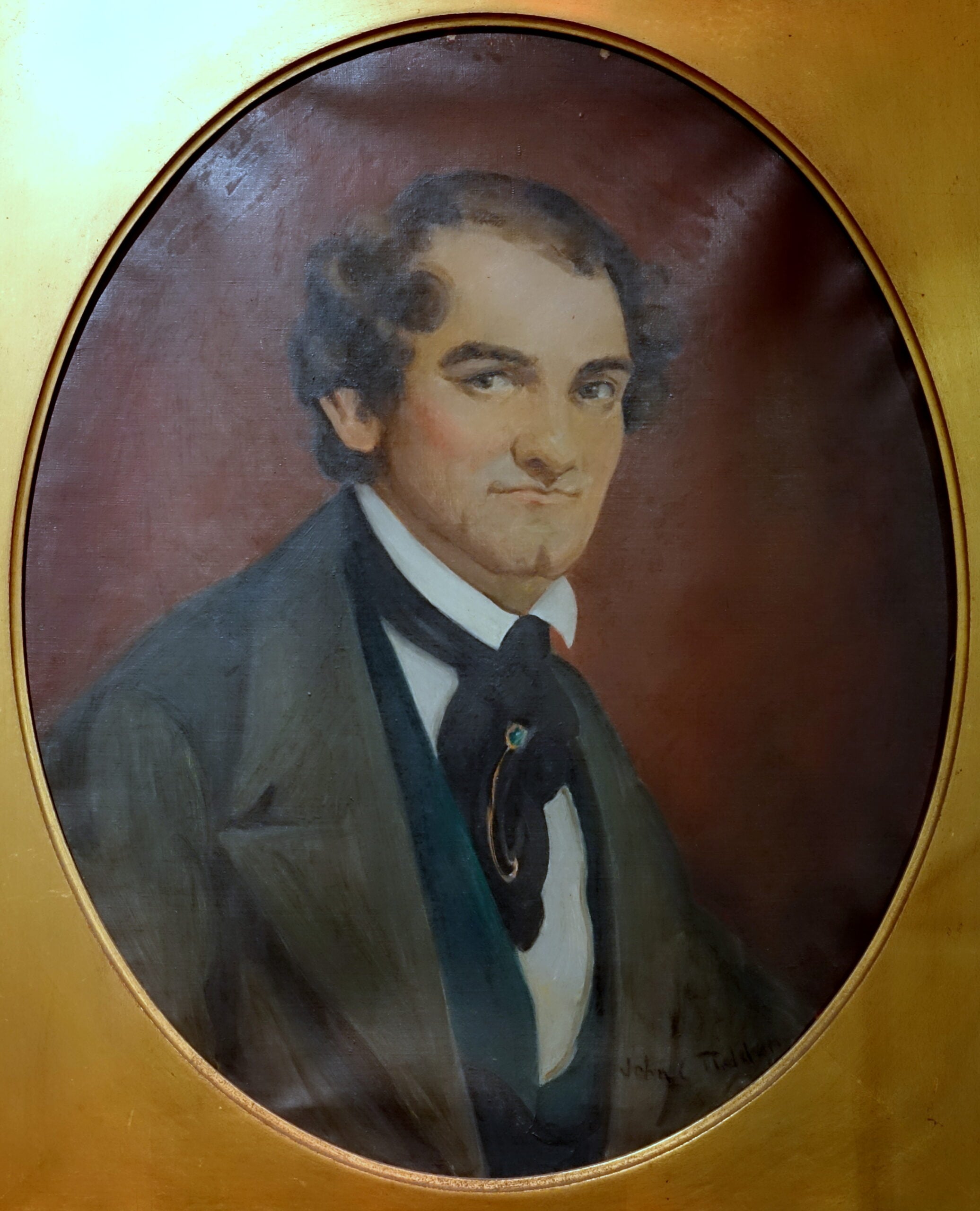 A painted portrait of a man with dark curly hair, wearing a dark coat, white shirt, and black cravat, set against a brown background in an oval frame.