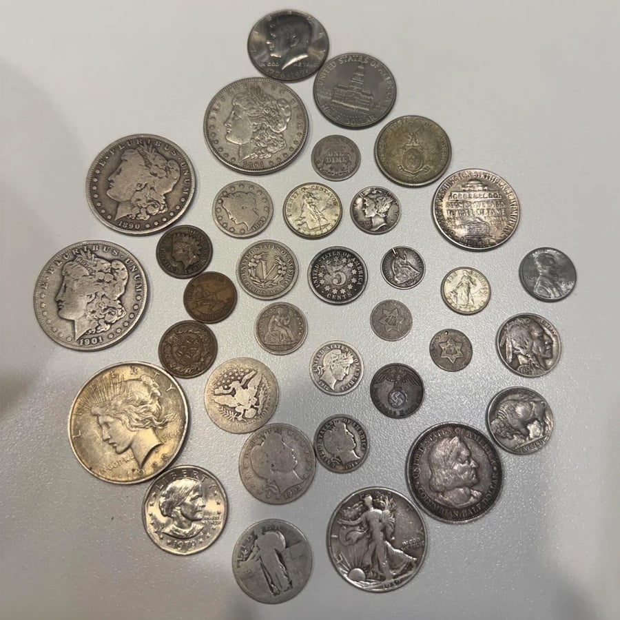 A collection of assorted vintage coins of various sizes, designs, and colors displayed on a light surface, including U.S. and foreign currency, some with visible dates and intricate details.