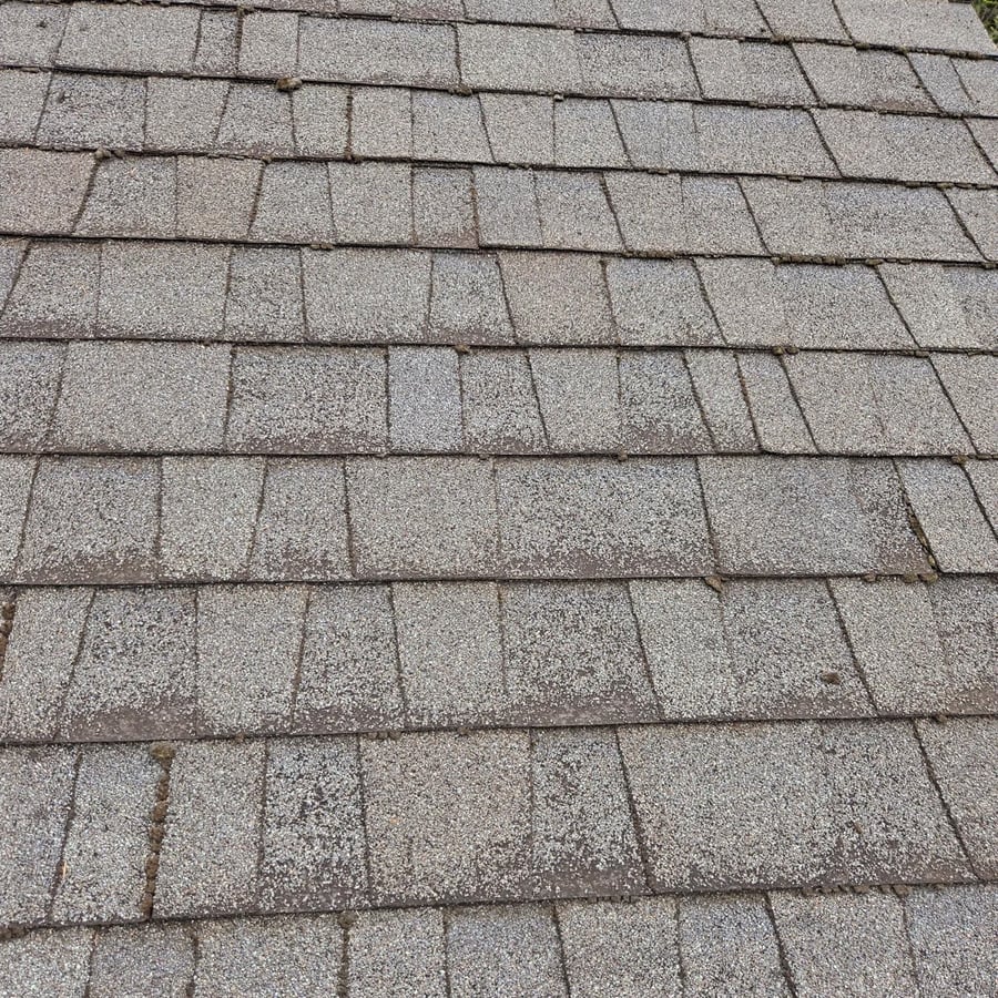 Close-up view of gray asphalt roof shingles arranged in overlapping rows, showing texture and granules on the surface.