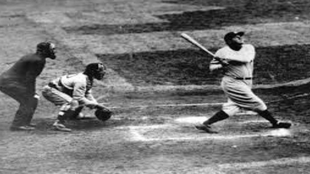 A baseball player swings his bat after hitting the ball while a catcher and umpire watch behind him at home plate during a game.