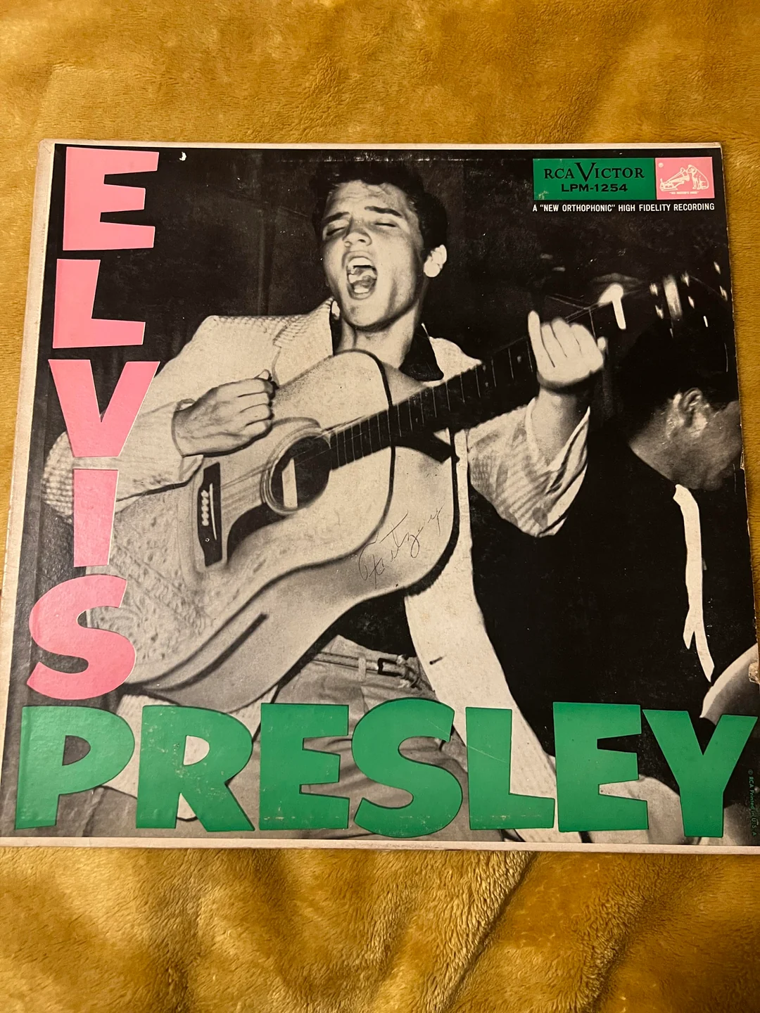Black-and-white album cover showing a man playing guitar and singing, with large pink text reading “ELVIS” and green text reading “PRESLEY.” RCA Victor and other label details are in the upper right corner.