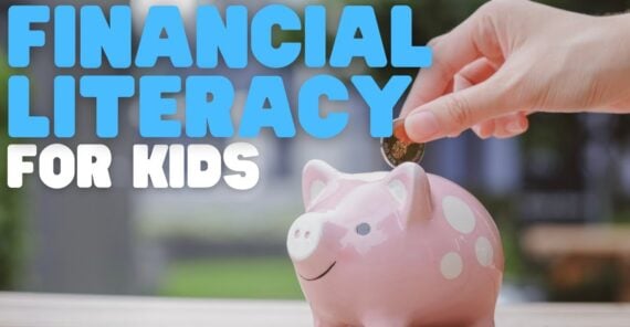 A hand places a coin into a pink piggy bank on a table. Large text reads “Financial Literacy for Kids.” The background is blurred greenery.