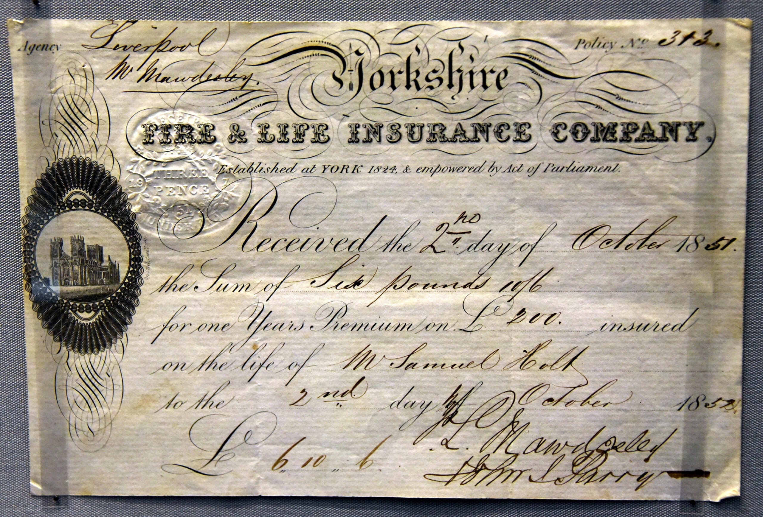 An 1851 insurance receipt from Yorkshire Fire & Life Insurance Company, handwritten, detailing payment of six pounds for a one-year premium on the life of Samuel Cole, featuring ornate script and official seals.