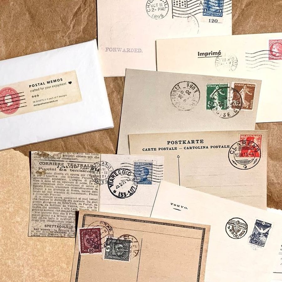 A variety of vintage postcards, envelopes, and stamps are arranged on a table. Some have postal markings and handwritten text, creating a nostalgic mail-themed display.