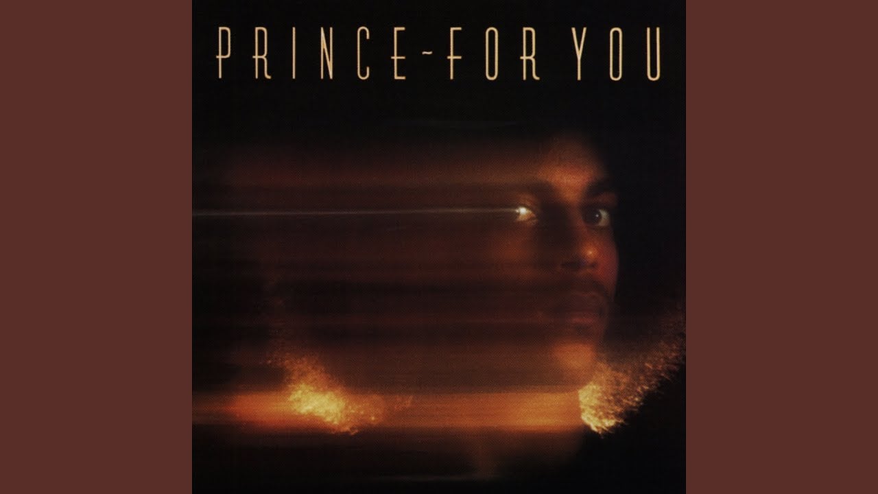 Album cover for “Prince - For You” featuring a blurred image of a face with Afro hair on a dark background, with the album title in thin, gold letters at the top.