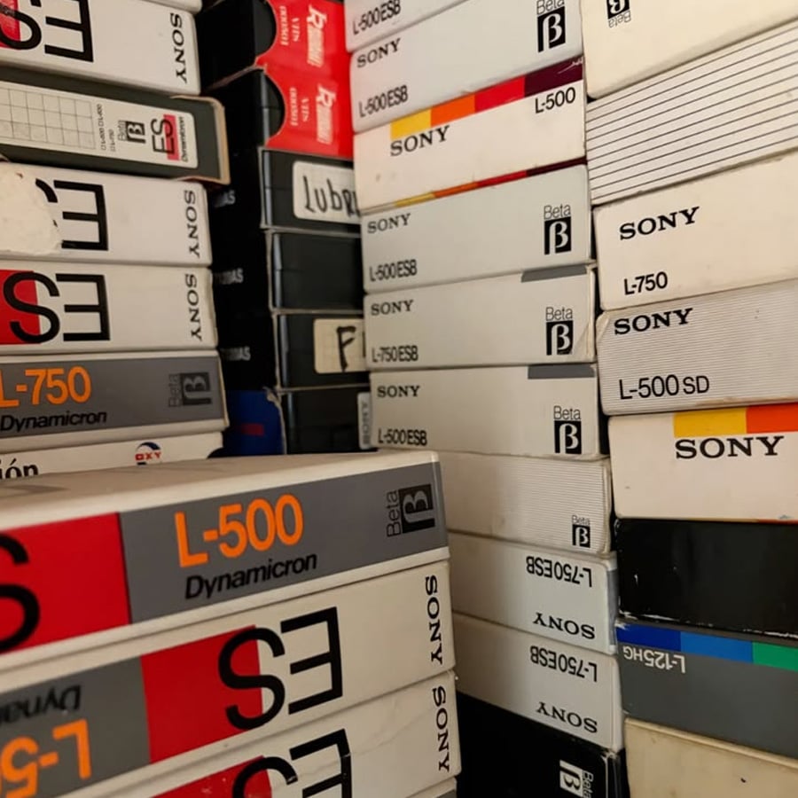 Stacks of vintage Sony Beta video cassette tapes are arranged closely together, showing labels like L-750 and L-500. The boxes display various designs, mostly white with bold text and logos.