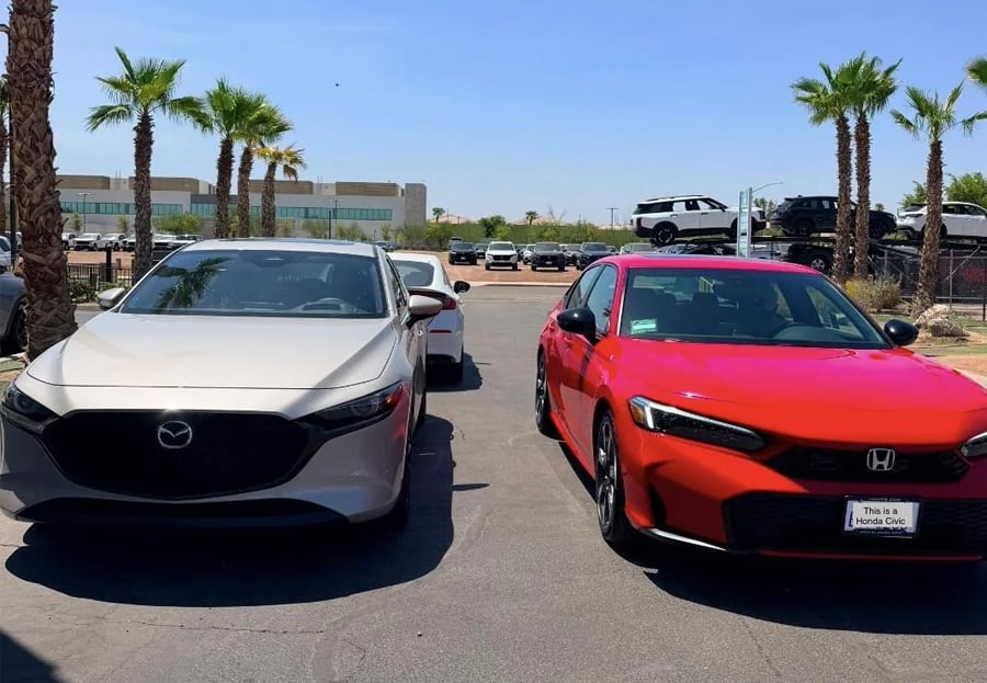 A silver Mazda and a red Honda Civic are parked side by side in a sunny parking lot with palm trees and other cars in the background.