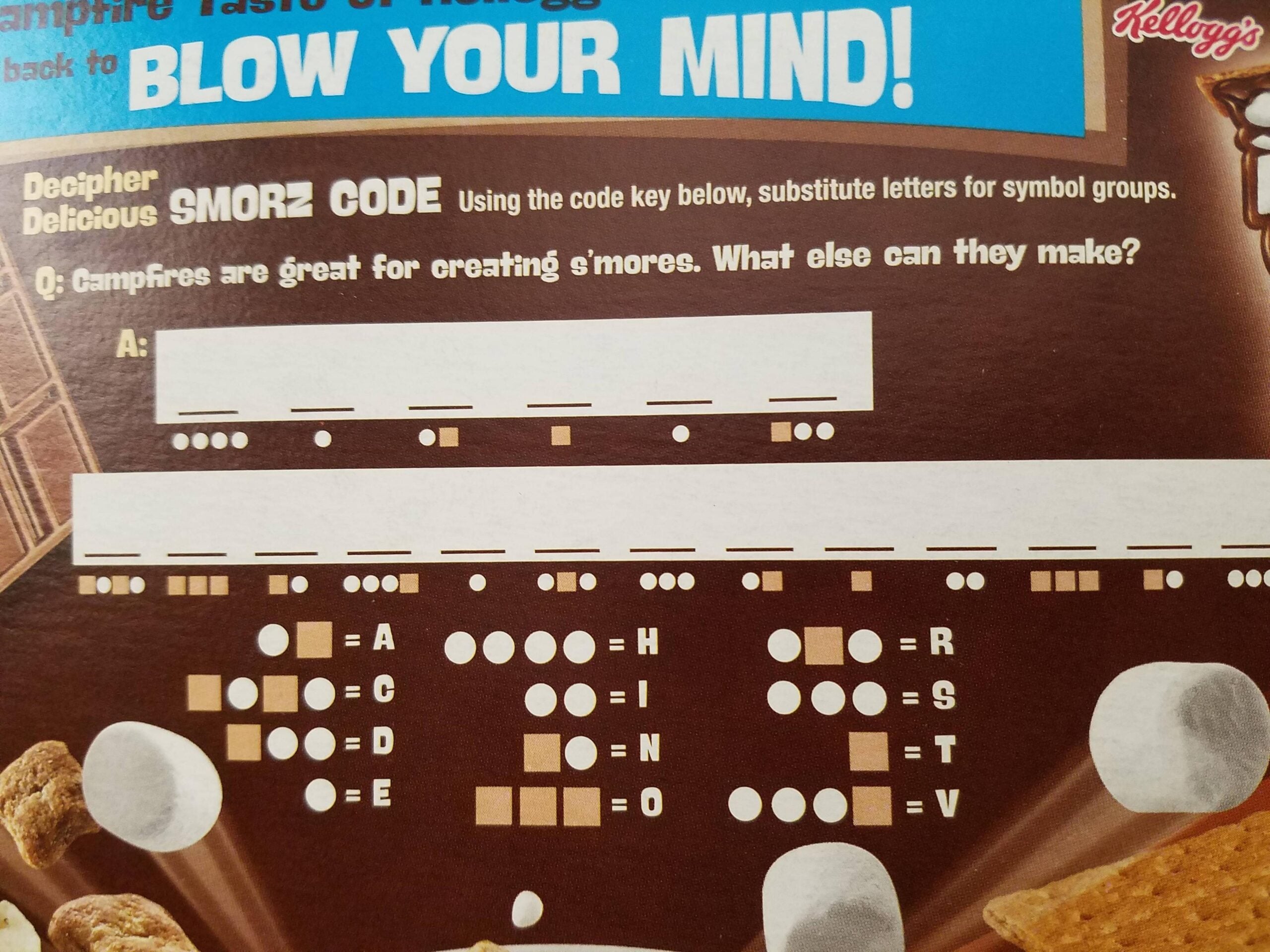 A cereal box features a s’mores-themed code with dots and lines to decipher, a question about campfires, decoding instructions, and scattered images of marshmallows and graham crackers.