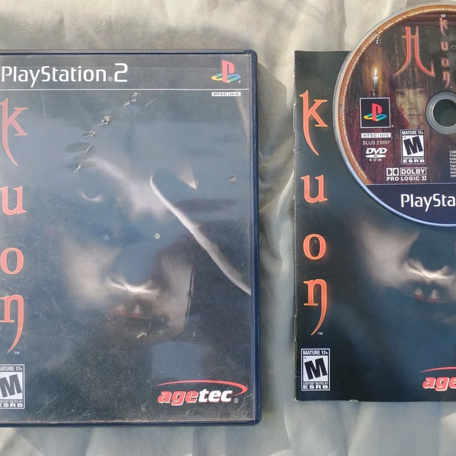 Kuon for PlayStation 2 shown with its case, game disc, and manual. The cover art depicts a haunting face and red Japanese-style text. All items are laid out on a gray surface.