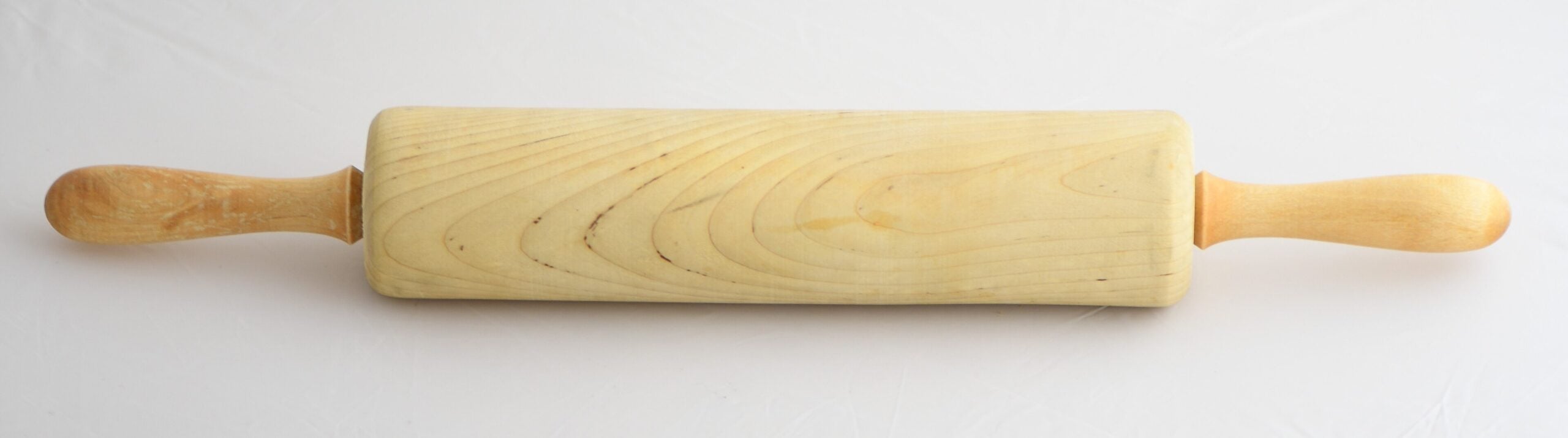 A wooden rolling pin with two handles is lying flat on a plain white surface.