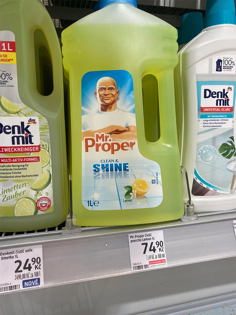 A 1-liter bottle of Mr. Proper Lemon cleaner with a smiling bald man on the label is displayed on a store shelf between other cleaning products. The price tag below reads 7,49 zł.