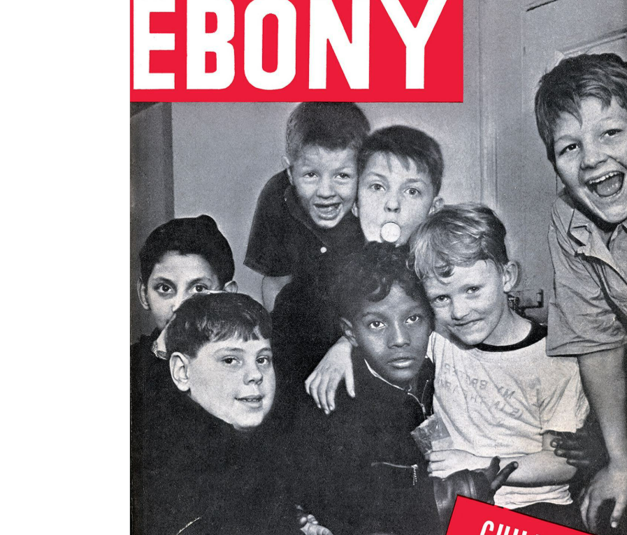 Black-and-white photo of six smiling children, of different races, huddled together and looking at the camera. The top of the image displays part of the word “EBONY” in bold white letters on a red background.
