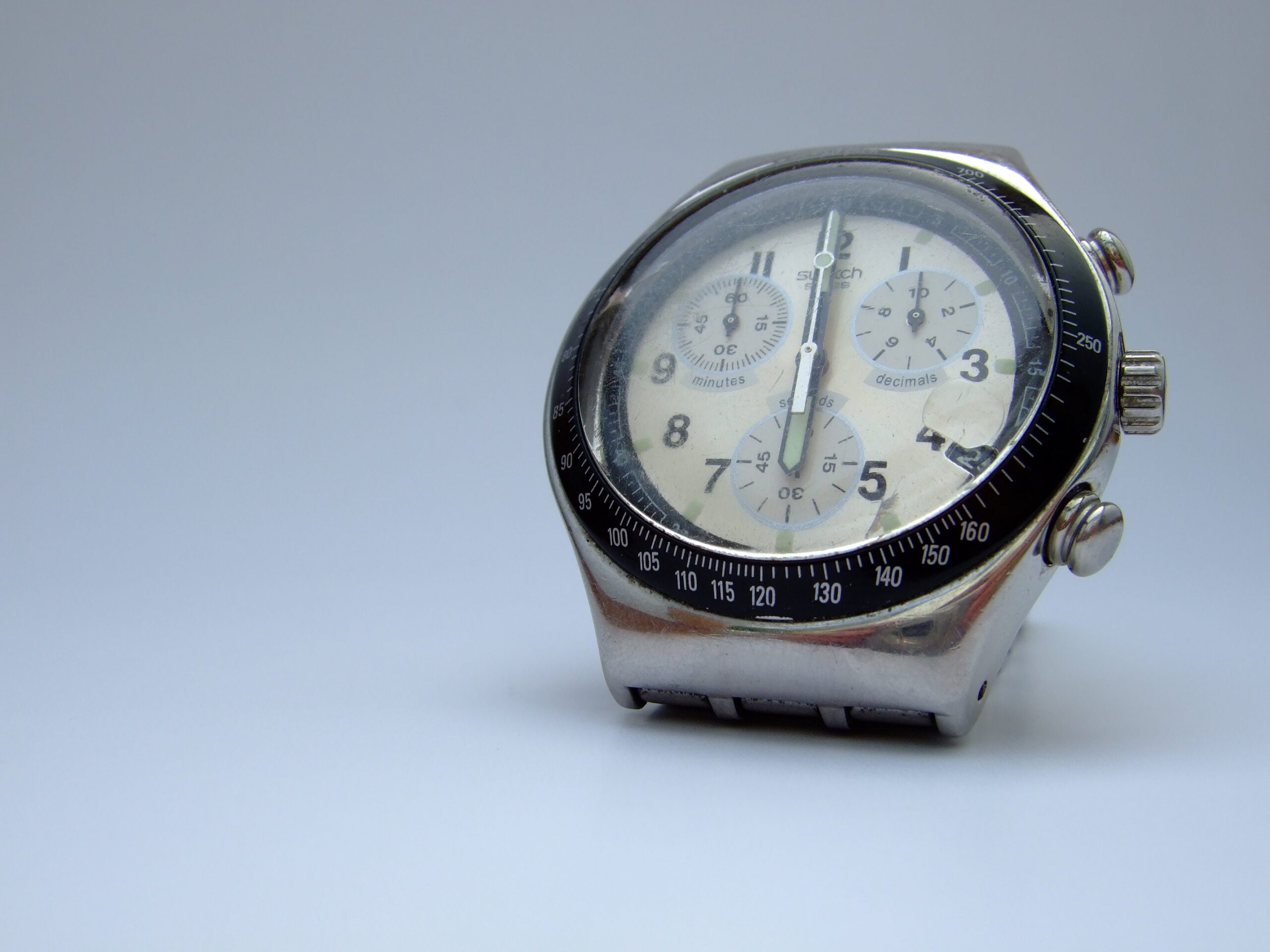 A silver analog chronograph wristwatch with a black bezel and three subdials is displayed against a plain white background.