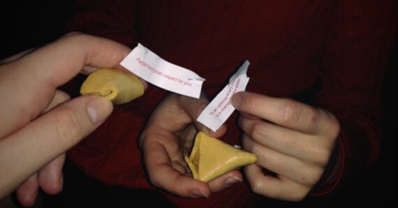 Two people hold broken fortune cookies. Each person holds a cookie and a paper fortune; one fortune reads, “People have great respect for you.” Both are set against a dark background.