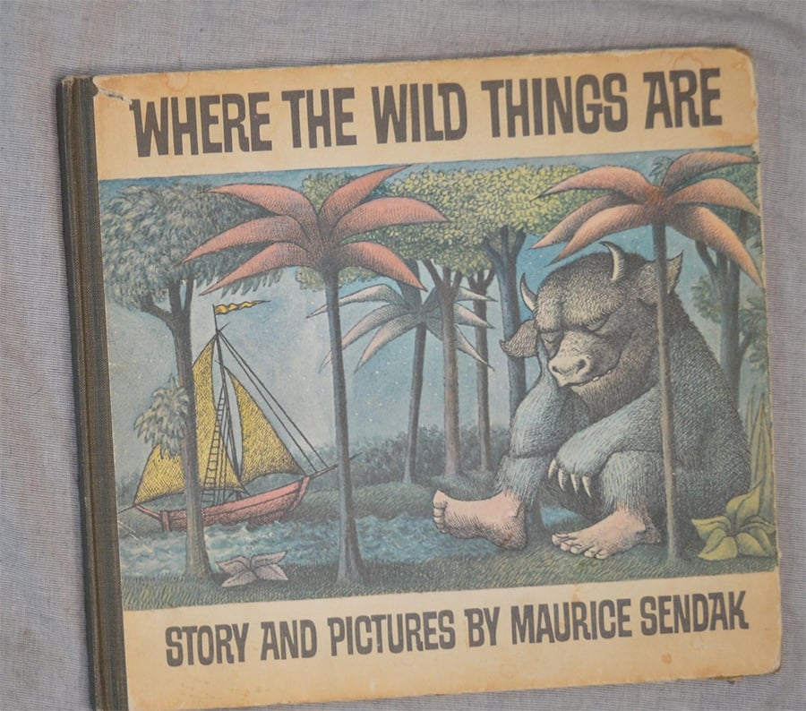 Cover of “Where the Wild Things Are” by Maurice Sendak, showing a large creature sitting by trees and a sailboat in the background, with the title in bold letters above.