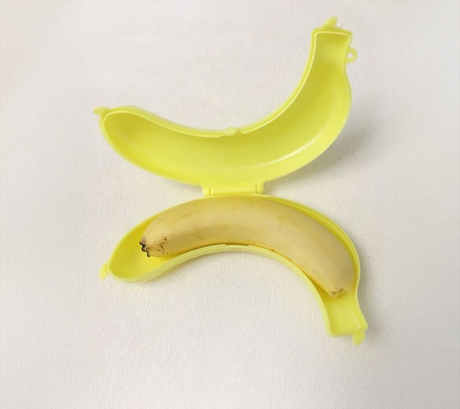 A peeled banana inside a yellow, banana-shaped plastic container, both placed on a white surface.