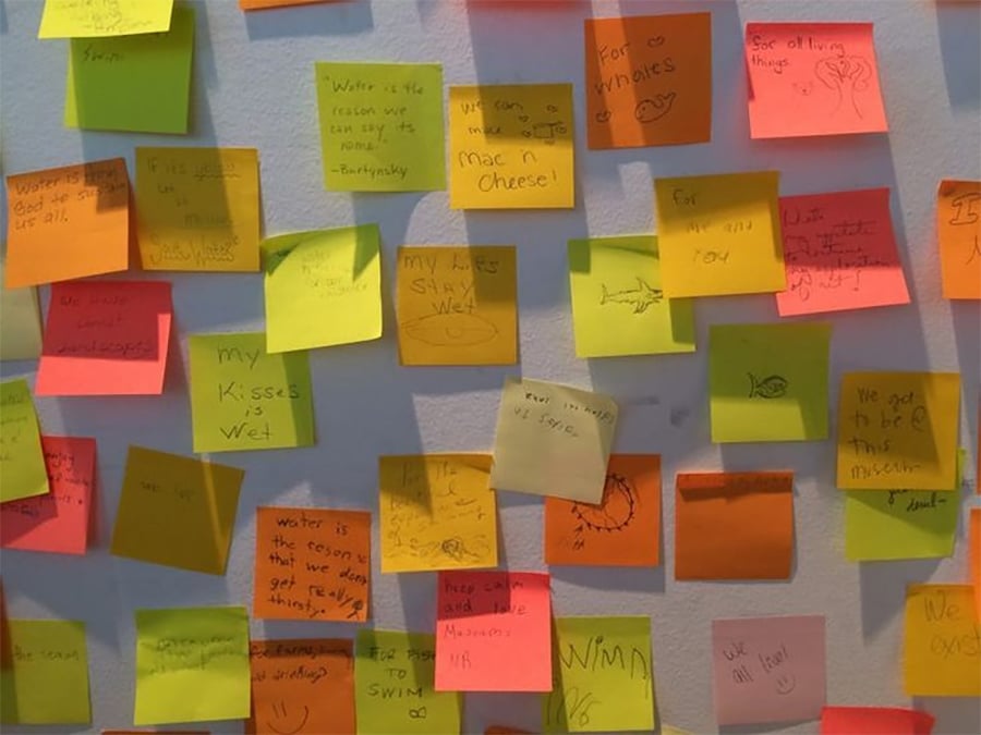 A wall covered in colorful sticky notes, each with handwritten messages and doodles, expressing thoughts, memories, and drawings in various colors like yellow, orange, green, and pink.