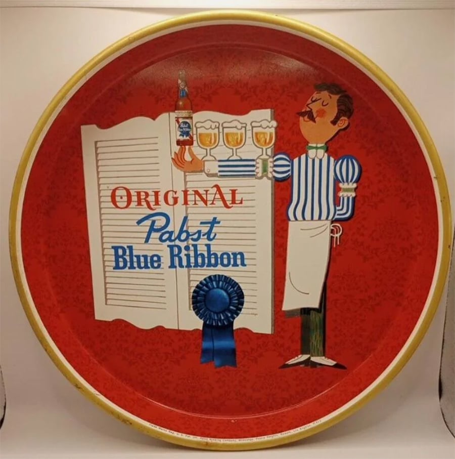 A vintage red tray featuring a cartoon waiter, three glasses of beer, and the text “Original Pabst Blue Ribbon” with a blue ribbon on it.