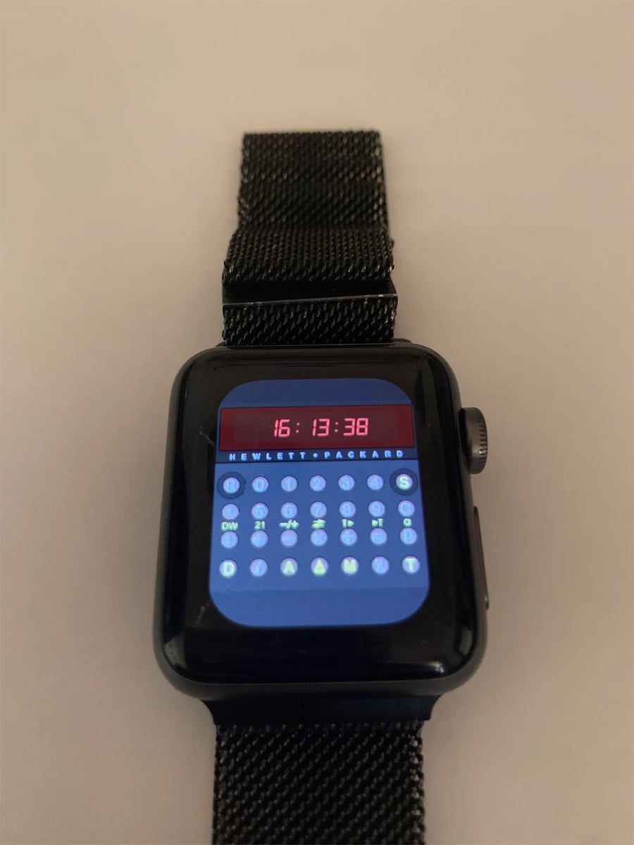 A black smartwatch displays a vintage calculator watch face with red digital time and calculator buttons. The watch has a black mesh strap and is set against a plain light background.
