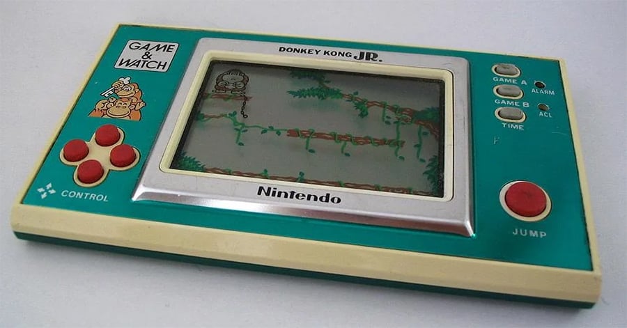 A vintage Nintendo Game & Watch handheld console featuring Donkey Kong Jr., with a small screen, red buttons, and a teal and cream casing.