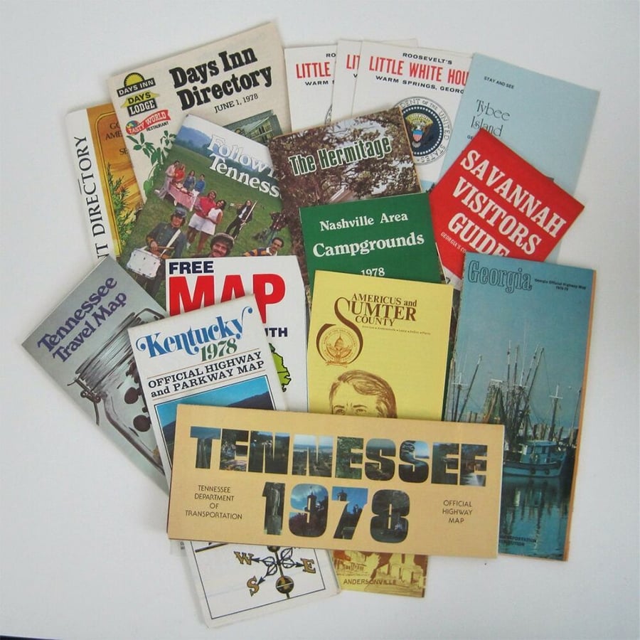A collection of vintage travel brochures and maps from the 1970s, including guides for Tennessee, Kentucky, Georgia, and various attractions, spread out on a white surface.