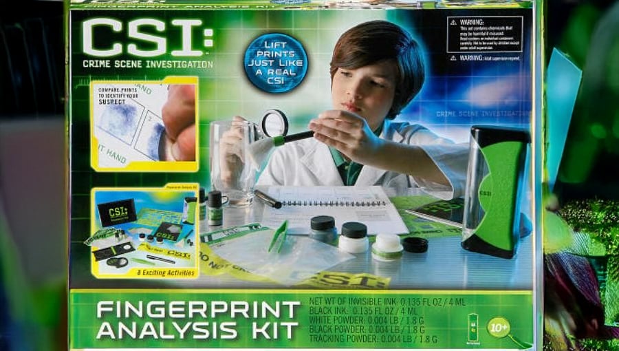 A CSI Fingerprint Analysis Kit box shows a child examining a test tube with various fingerprinting tools and accessories displayed, designed for crime scene investigation play.