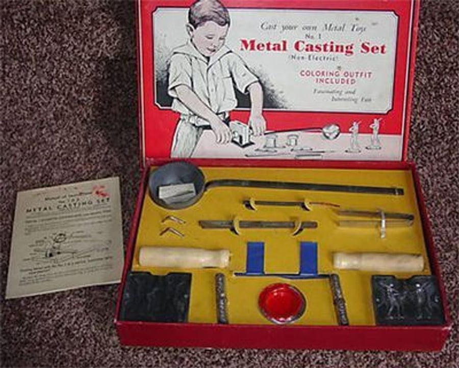 Vintage metal casting set with tools and molds in a red box, featuring instructions and a drawing of a boy using the set on the inner lid. Kit contents are neatly arranged inside yellow and red packaging.
