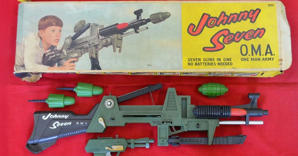 Vintage Johnny Seven O.M.A. toy gun set with green and black plastic rifle, grenade accessories, and original box featuring a boy aiming the toy. Box text reads “Seven guns in one. No batteries needed.”