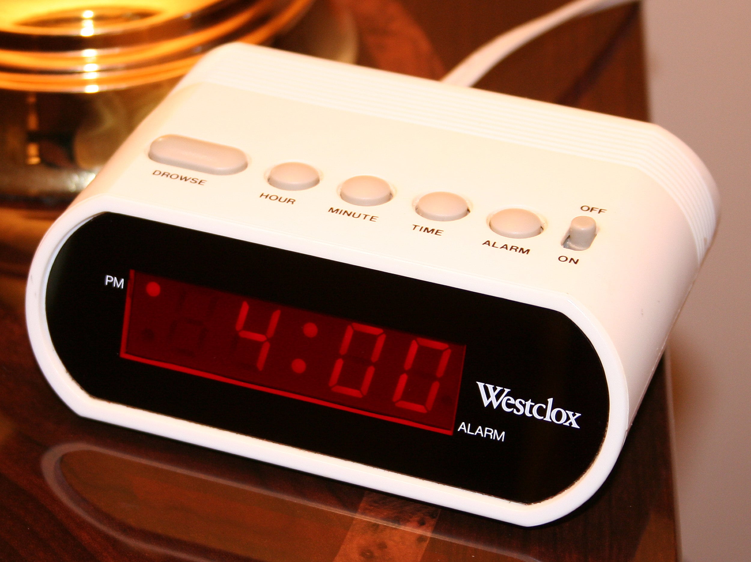 A white digital alarm clock with a red LED display shows the time as 4:00 PM. Several gray buttons and a switch are on top, labeled Browse, Hour, Minute, Time, Alarm, Off, and On.