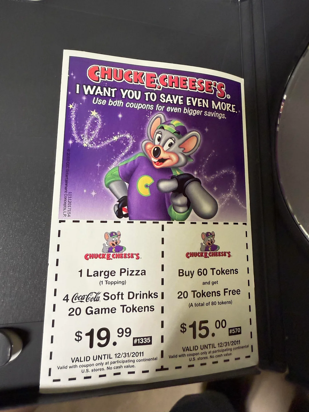 Two Chuck E. Cheese’s coupons for a large pizza, four soft drinks, and 20 game tokens, plus a buy 60 tokens get 20 free deal, both expiring 12/31/2011. A mouse mascot is featured above the coupons.