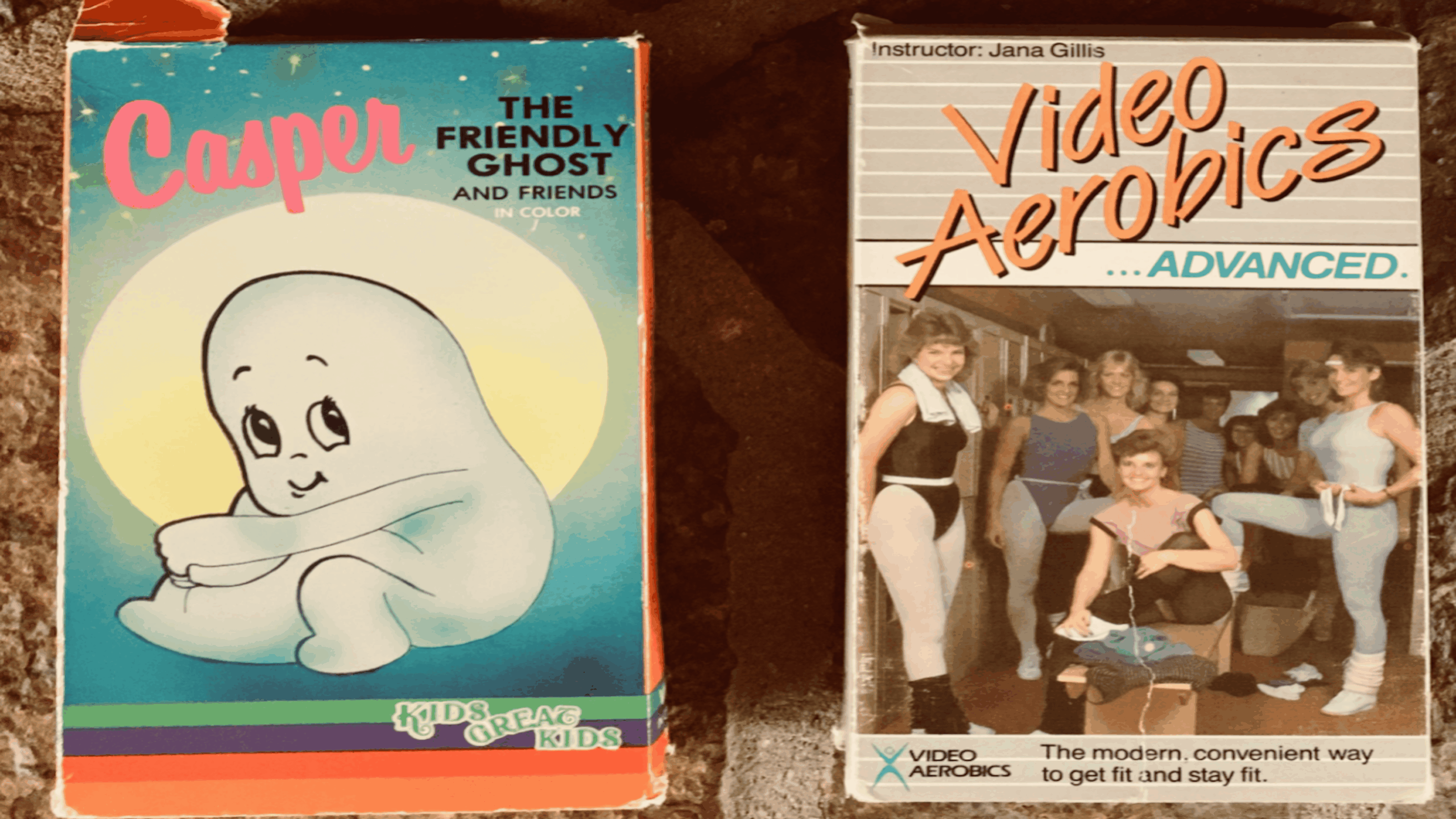 Two VHS tapes: one with cartoon ghost Casper on the cover, the other titled “Video Aerobics ...Advanced” showing women in workout attire, led by an instructor, in an exercise studio.
