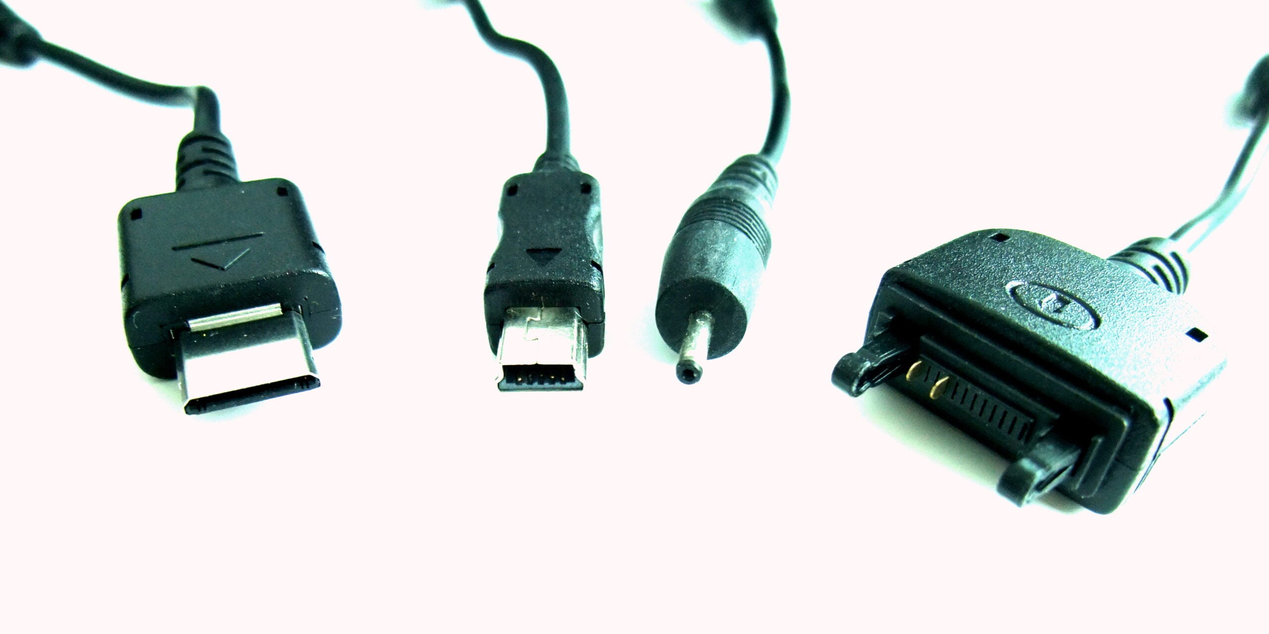 Four black electronic charging cables with different connector types are lined up against a white background, including USB and proprietary connectors.