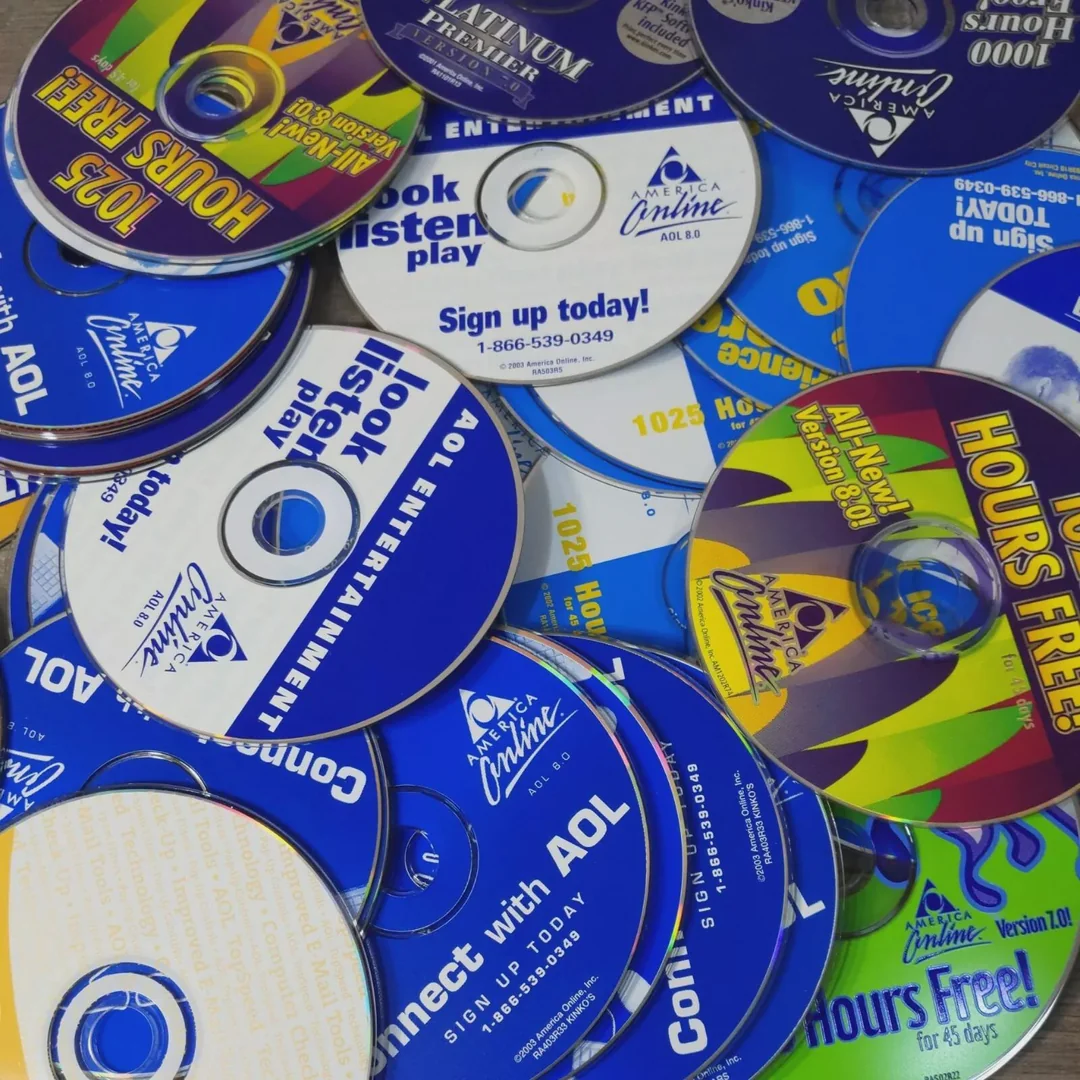 A pile of colorful AOL installation CDs, each offering hours of free internet, with text promoting AOL signup and connection services visible on the discs.