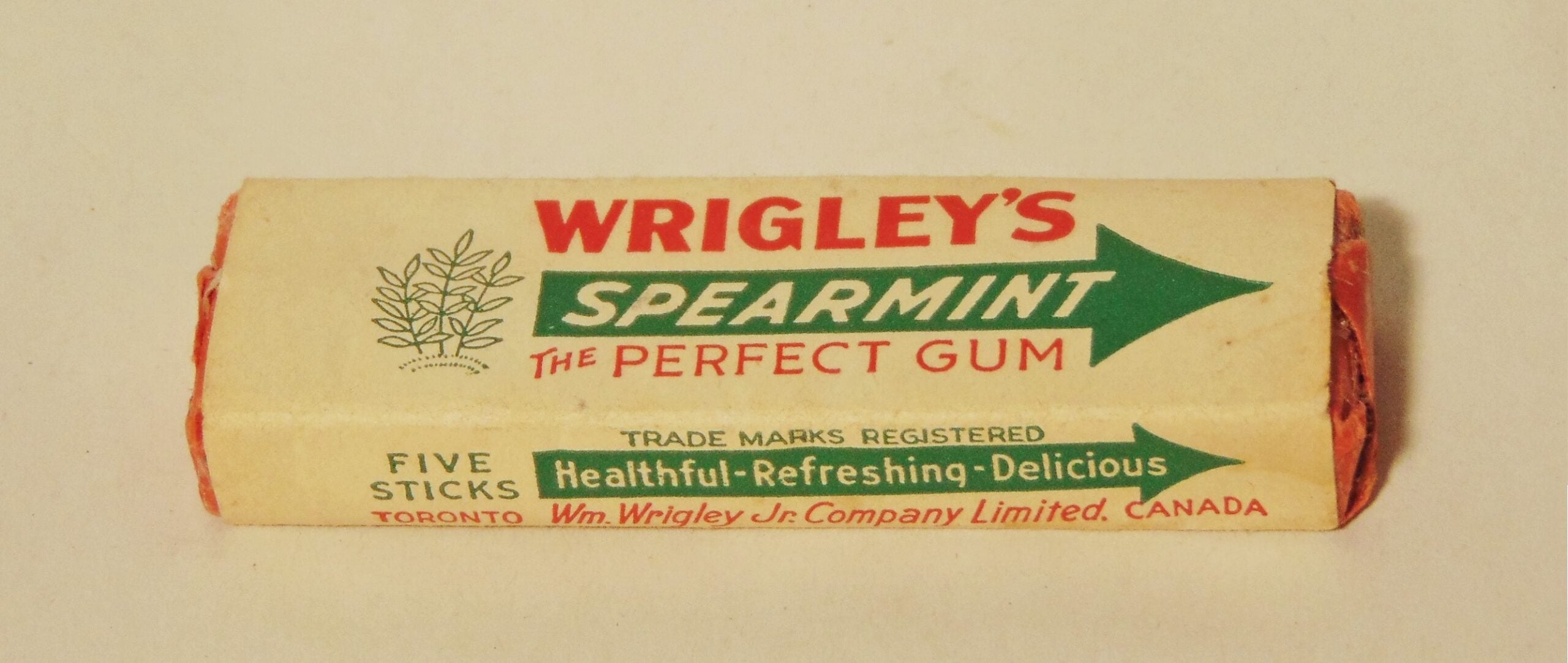 A vintage package of Wrigley’s Spearmint gum with red and green text, labeled “The Perfect Gum,” containing five sticks. The packaging also mentions “Healthful-Refreshing-Delicious.”
