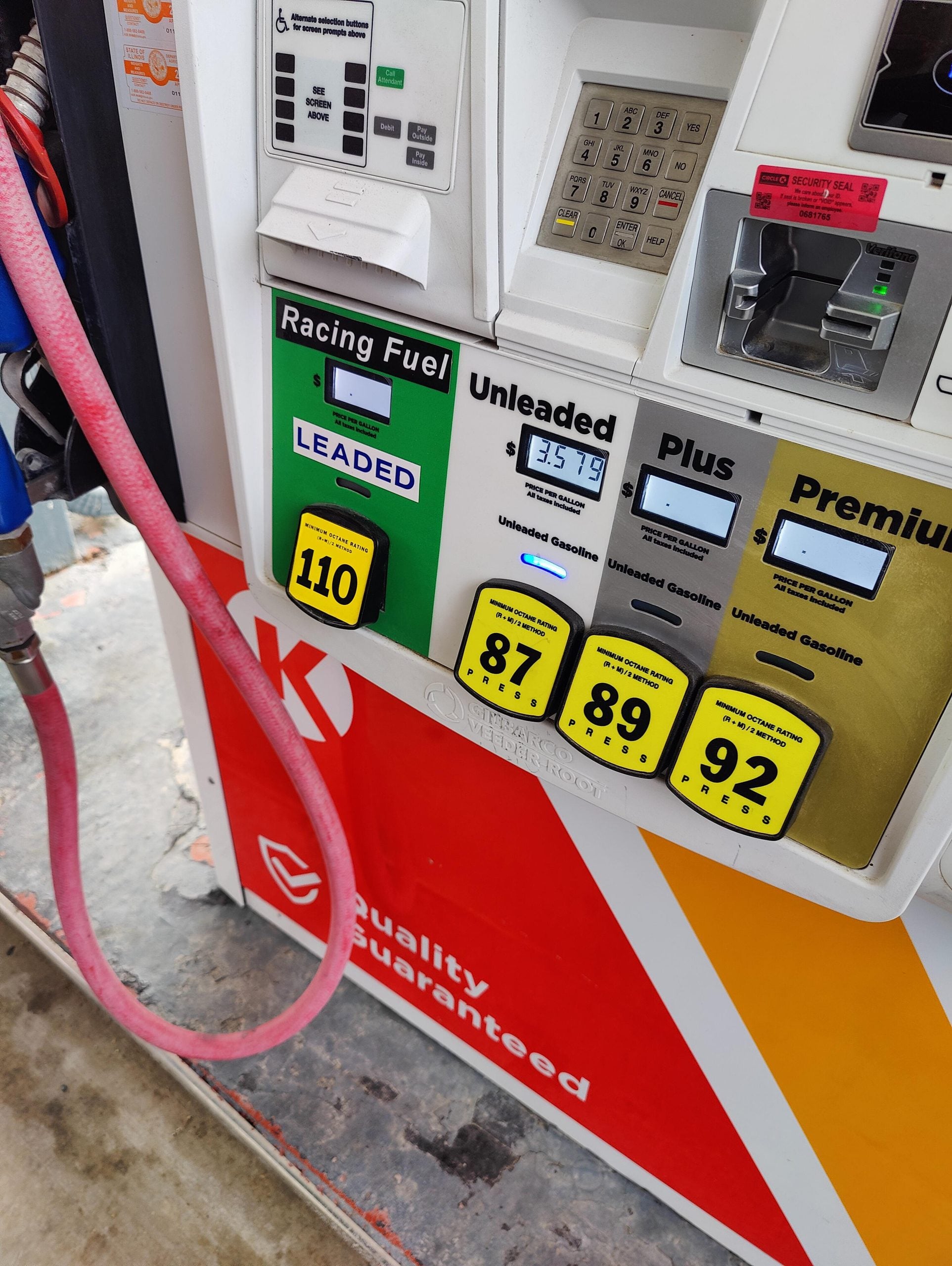 A gas pump displays options for Racing Fuel, Unleaded, Plus, and Premium with octane ratings 110, 87, 89, and 92. A pink fuel hose is attached, and the Circle K logo and “Quality Guaranteed” are visible.