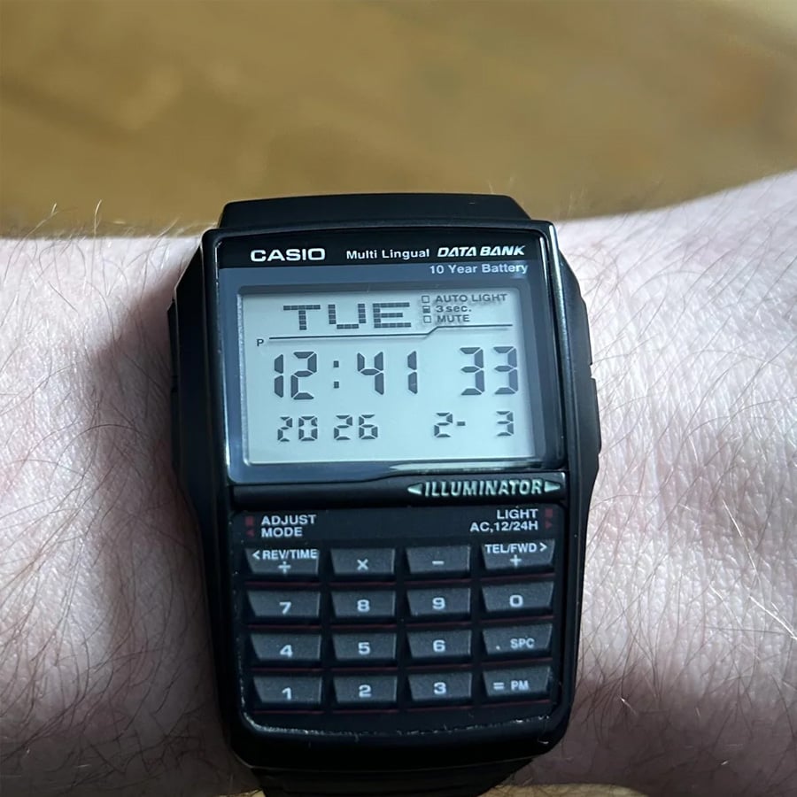 A Casio Data Bank digital wristwatch with a calculator is worn on a person’s wrist, displaying the time as 12:41:33, the date as Tuesday, February 3, and the year 2026.