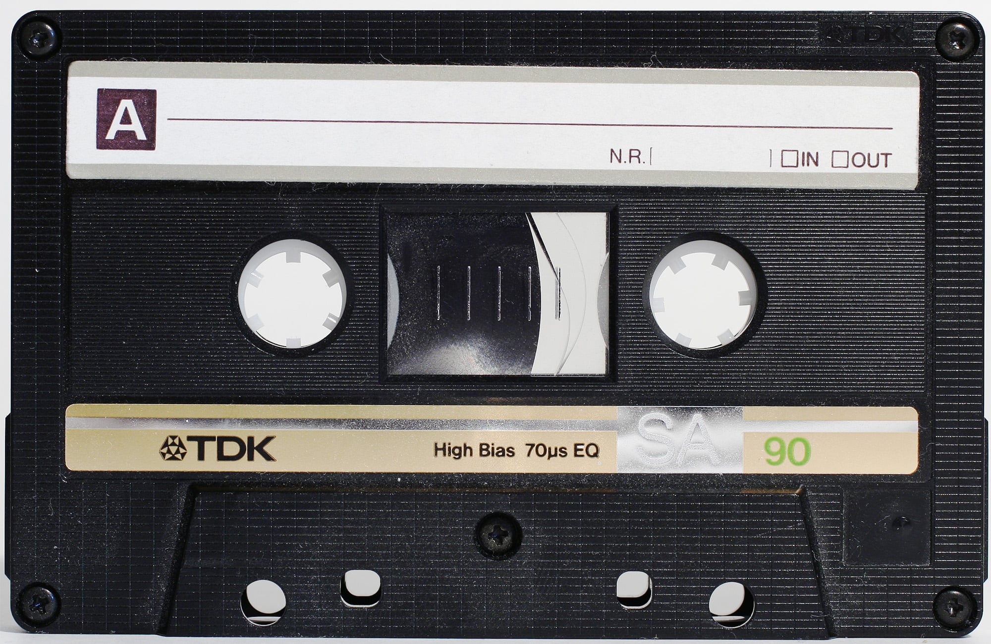 A black TDK SA90 audio cassette tape with a white label marked “A,” and a beige strip labeled “High Bias 70µs EQ.” The tape reels and central window are visible.