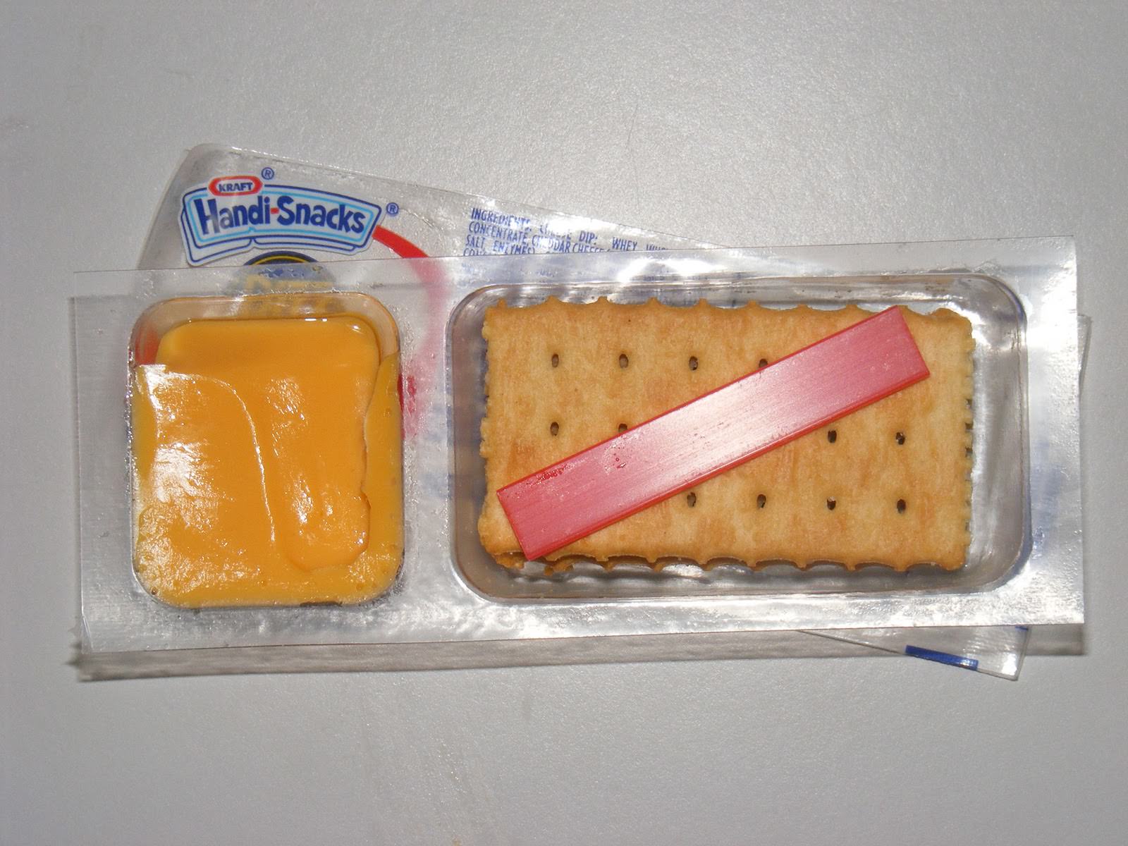 A Handi-Snacks pack with crackers, processed cheese, and a small red plastic stick for spreading the cheese.