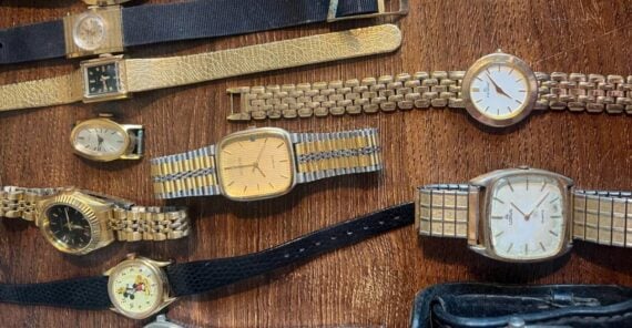 A collection of various vintage wristwatches with leather, metal, and jeweled bands is displayed on a wooden surface.