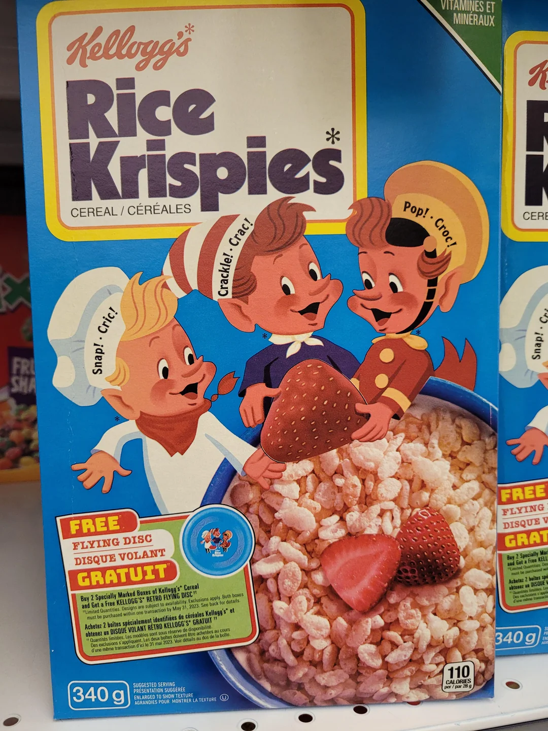 A box of Kellogg’s Rice Krispies cereal features cartoon mascots Snap, Crackle, and Pop above a bowl of cereal with strawberries. The box advertises a free flying disc offer in English and French.